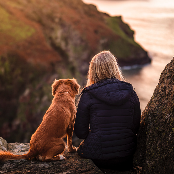Woman and dog on a cliff overlooking the sea