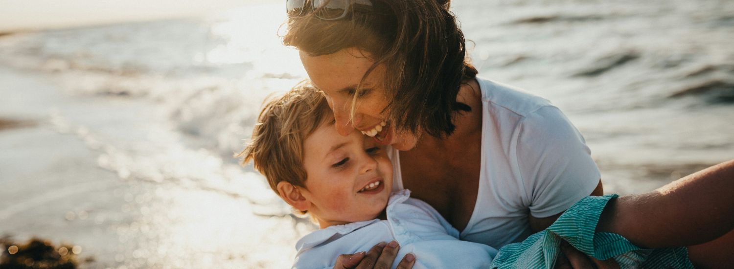 Woman smiling and holding a child on the beach