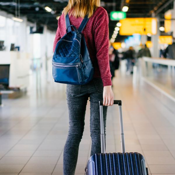 Woman at an airport with a suitcase and backpack