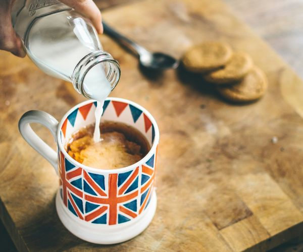 Person pouring milk into a cup of tea