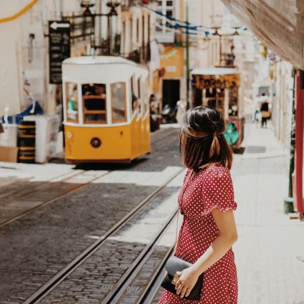 Woman in a polka dot dress looking at a yellow tram in Portugal