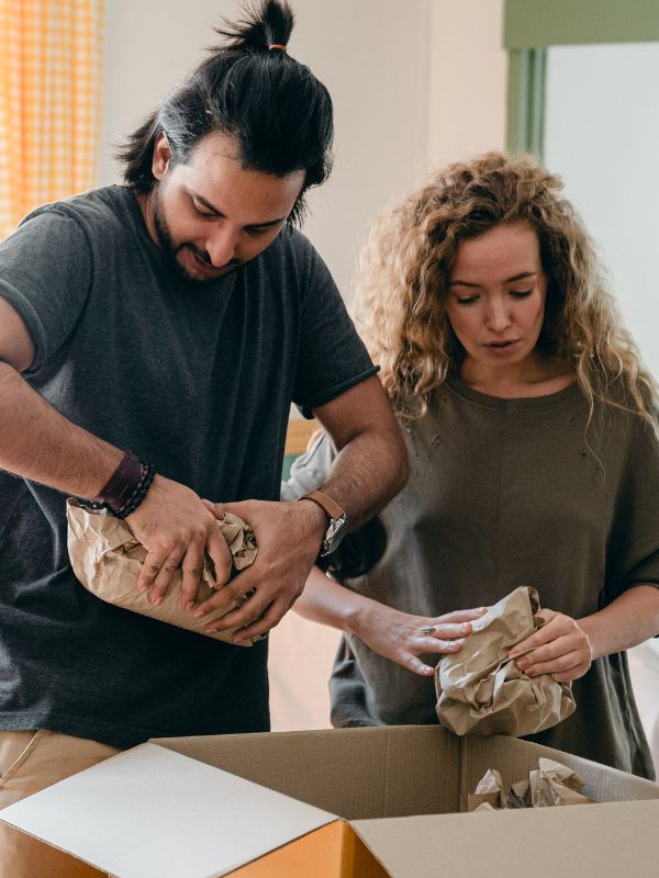 Couple wrapping belongings in packing paper