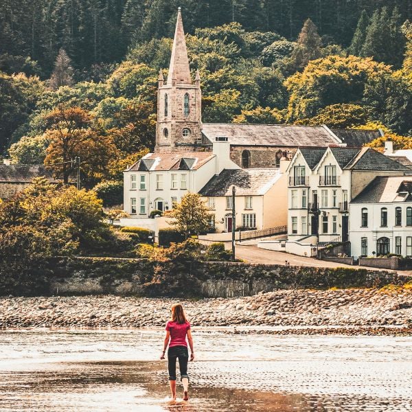 Woman walking barefoot on a beach in Ireland