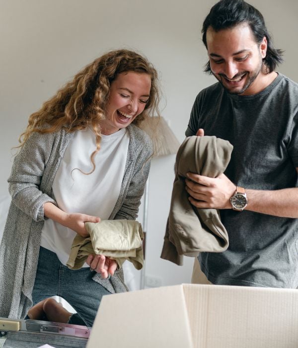 Laughing couple packing items into a cardboard box