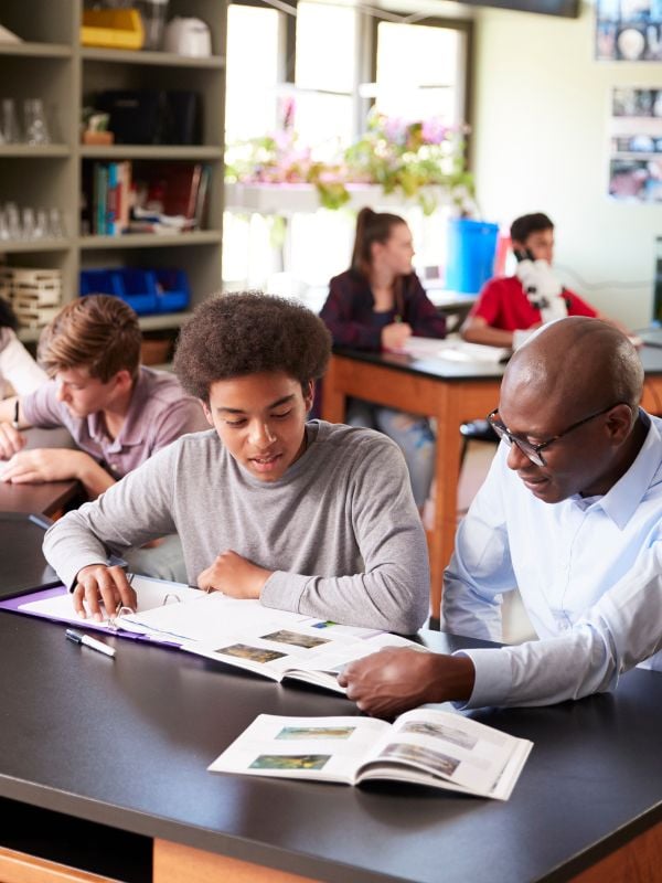 Boy Being Helped By A Teacher In A Classroom