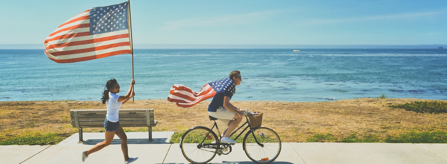 Smiling people waving an American flag by the sea