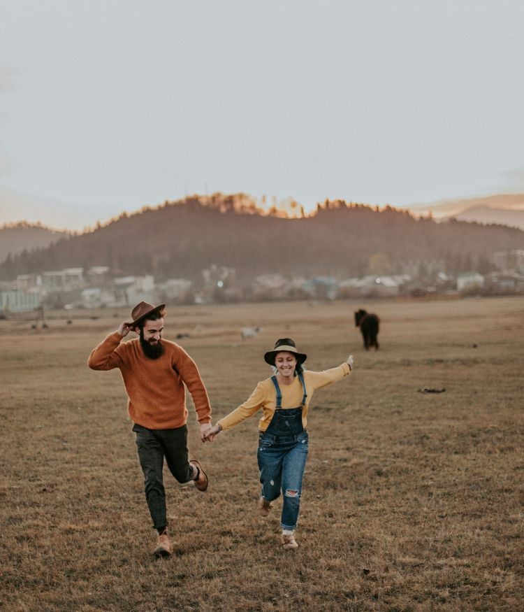 Smiling people running through a field in America