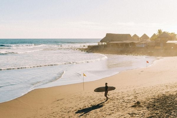 Surfer walking across a beach in Salvador in Brazil 